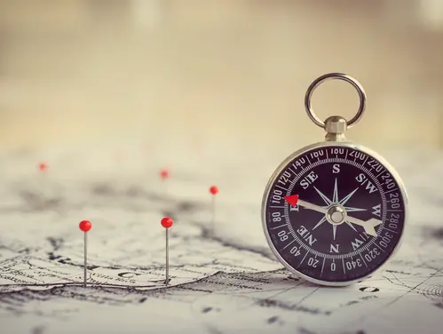 push pins marking a route on a map with a compass to the side